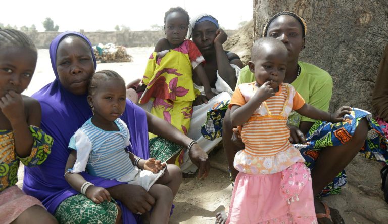 In this photo taken on Monday, Feb. 18, 2019, Woman and their children displaced by Islamist extremist sit in the shade at Malkohi camp for Nigerians who have fled Boko Haram violence in Yola, Nigeria.  