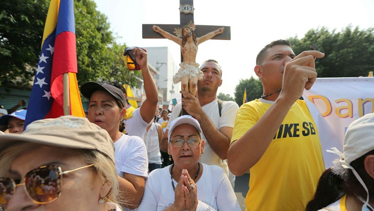 Opposition members pray during clashes with the Bolivarian National Guard in Urena, Venezuela.