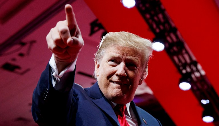 President Trump points to the cheering audience as he arrives to speak at an event.