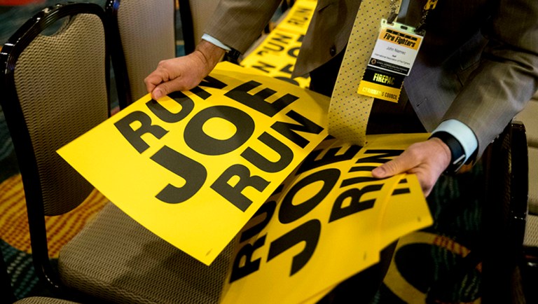 Workers lay out signs that read "Run Joe Run" ahead of a speech by former Vice President Joe Biden.