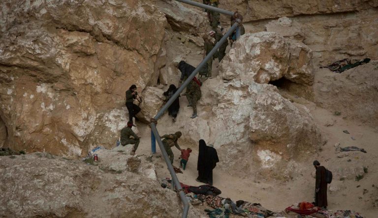 People who left the besieged Islamic State-held village of Baghouz, Syria, scramble up a rocky hillside to be checked by U.S-backed Syrian Democratic Forces Thursday, March 14, 2019. 