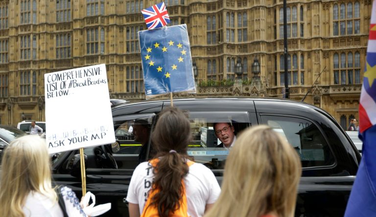 In this Wednesday, June 20, 2018  photo, a man in a passing taxi shouts his disagreement at anti-Brexit, pro-EU supporters protesting backdropped by the Houses of Parliament in London.