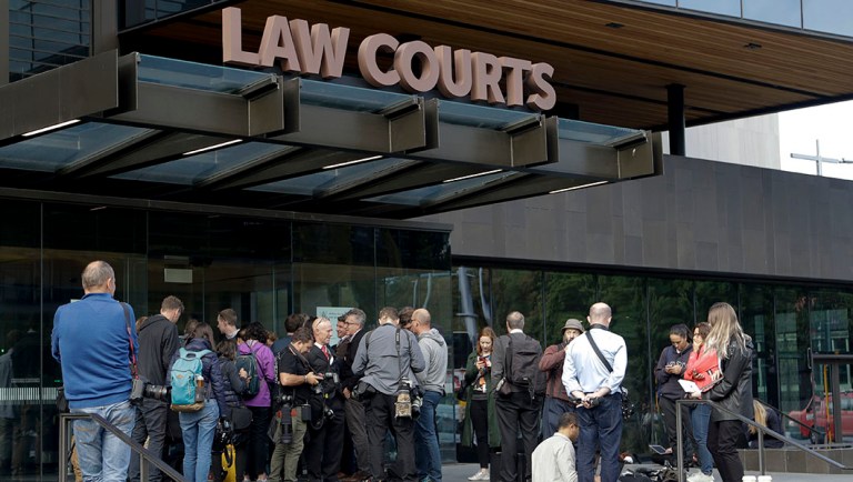 Members of the media wait outside the district court building for word on the man arrested in connection with the mass shootings at two mosques in Christchurch, New Zealand.