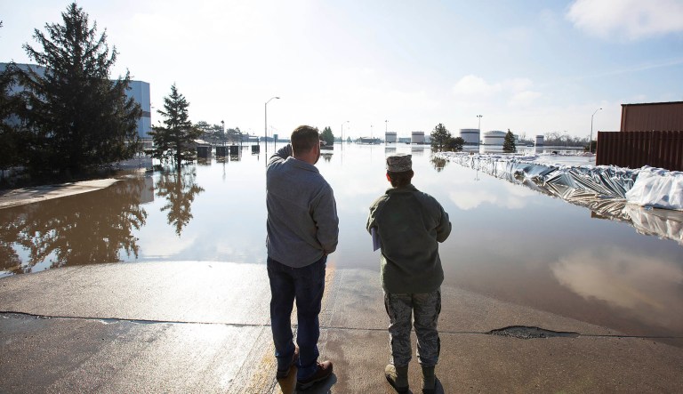 Luke Thomas and Air Force Tech Sgt. Vanessa Vidaurre look at a flooded portion of Offutt Air Force Base, Sunday, March 17, 2019, in Bellevue, Neb.