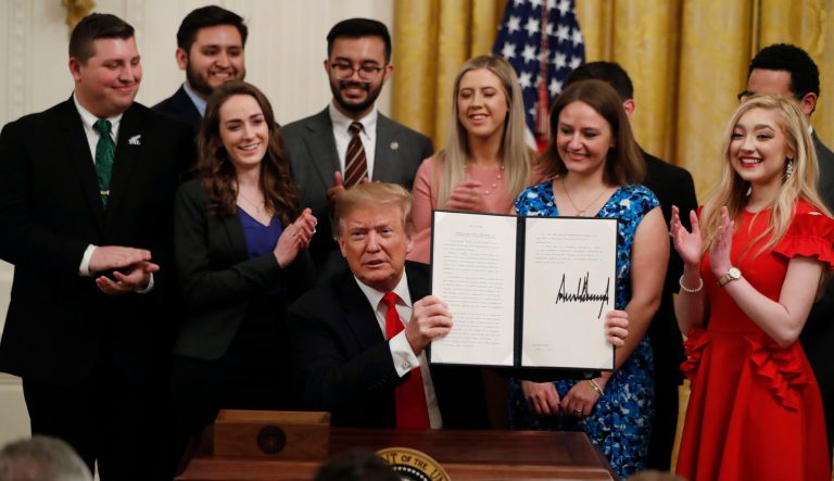 President Donald Trump holds up an executive order requiring colleges to certify that their policies support free speech as a condition of receiving federal research grants, after signing, Thursday March 21, 2019, in the East Room of the White House in Washington. 