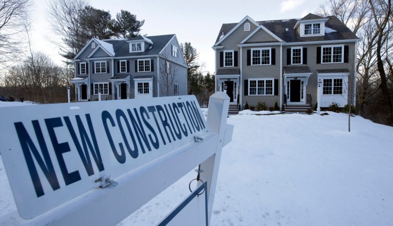 In this Feb. 21, 2019, photo a newly constructed homes sit near a sign in Natick, Mass. 