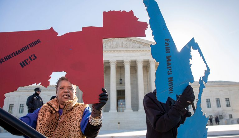 Activists at the Supreme Court opposed to partisan gerrymandering hold up representations of congressional districts from North Carolina, left, and Maryland, right, as justices hear arguments about the practice of political parties manipulating the boundary of a congressional district to unfairly benefit one party over another, in Washington, Tuesday, March 26, 2019. 