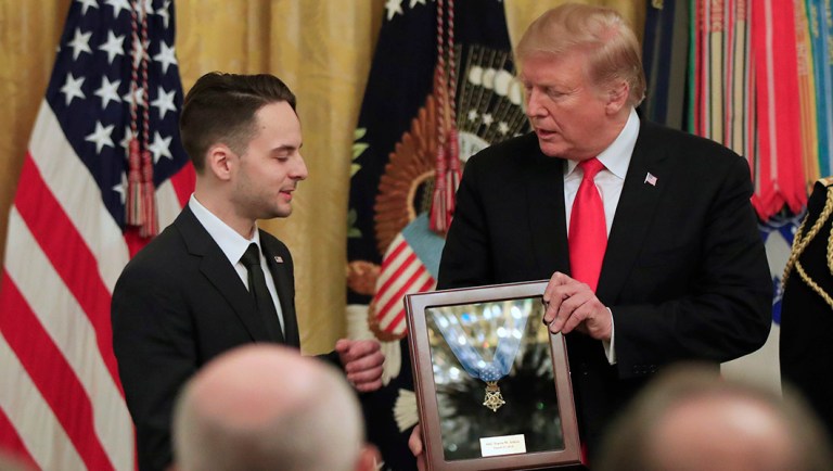 Trevor Oliver accepts the Medal of Honor from President Trump, presented to his father, Army Staff Sgt. Travis Atkins in recognition for conspicuous gallantry in Iraq in June 2007.