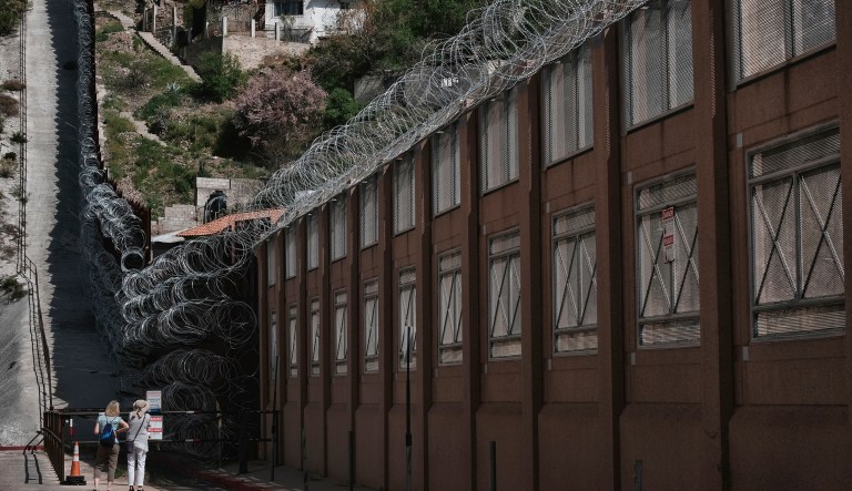 In this March 30, 2019 photo, a tourists take photos of the razor-wire-covered border wall that separates Nogales, Ariz. at left, and Nogales, Mexico on the right.