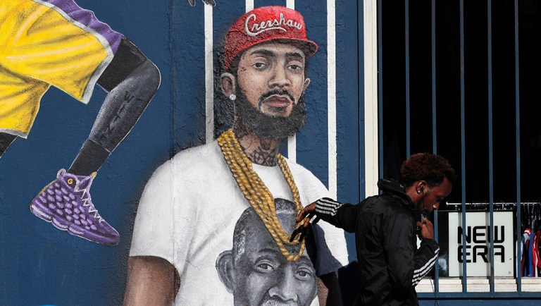 A man touches a mural depicting slain rapper Nipsey Hussle.