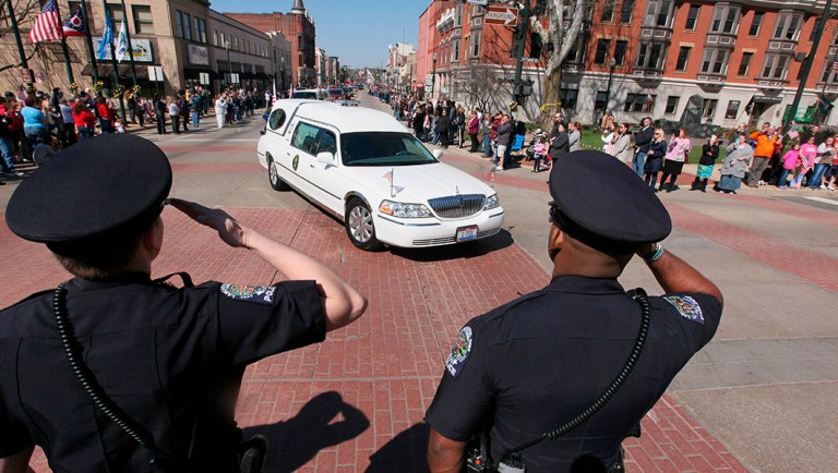 Police officers salute as the procession for Army Spc. Joseph Collette makes it's through Lancaster, Ohio.