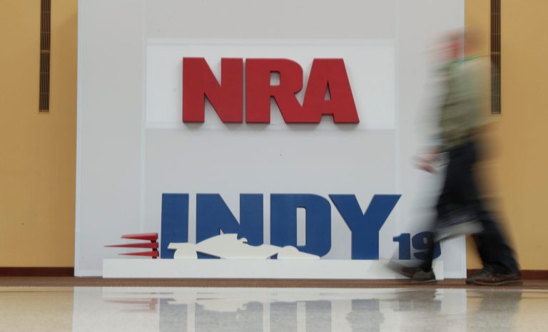 A visitor to the at the National Rifle Association Annual Meeting walks past signage for the event in Indianapolis, Saturday, April 27, 2019. 