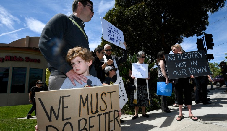 Kyle Fox, 4, and his father Brady Fox hold a sign at a vigil held to support the victims of Chabad of Poway synagogue shooting, Sunday, April 28, 2019, in Poway, Calif. A man opened fire Saturday inside the synagogue near San Diego as worshippers celebrated the last day of a major Jewish holiday.