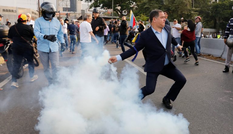 An opponent to Venezuela's President Nicolas Maduro returns a tear gas canister to soldiers who launched it at a small group of civilians and rebel troops gathered outside La Carlota air base in Caracas, Venezuela, Tuesday, April 30, 2019. Venezuelan opposition leader Juan GuaidÃ³ took to the streets with activist Leopoldo Lopez and a small contingent of heavily armed troops early Tuesday in a bold and risky call for the military to rise up and oust socialist leader Nicolas Maduro. 