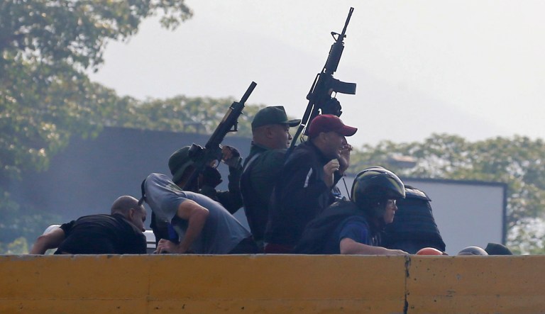 Rebel troops who are rising up against the government of Venezuela's President Nicolas Maduro fire their weapons from an overpass outside La Carlota military airbase where loyal troops are located in Caracas, Venezuela, Tuesday, April 30, 2019.