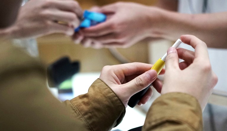 FILE - In this Oct. 22, 2018 file photo, visitors try out a pen-like "heat-not-burn" device at an IQOS store at Ginza in Tokyo. On Tuesday, April 30, 2019, the U.S. Food and Drug Administration said it will allow Philip Morris International to sell the cigarette alternative that heats tobacco without burning it. 