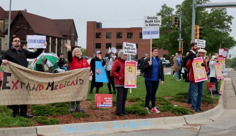 Advocates for expanding Medicaid in Kansas stage a protest outside the entrance to the Statehouse parking garage as lawmakers, staffers and others drive in, Wednesday, May 1, 2019, in Topeka, Kan. 