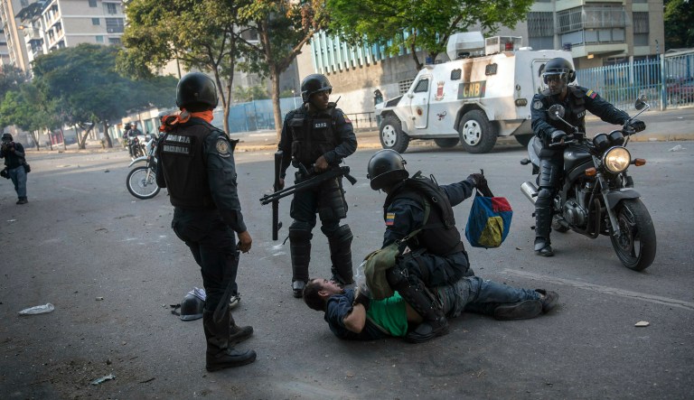 National Police detain an anti-government protester near the La Carlota airbase during clashes between the two sides in Caracas, Venezuela, Wednesday, May 1, 2019. Opposition leader Juan Guaido called for Venezuelans to fill streets around the country Wednesday to demand President Nicolas Maduro's ouster. Maduro is also calling for his supporters to rally.