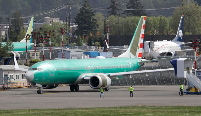 Workers stand near a Boeing 737 MAX 8 jetliner being built for American Airlines prior to a test flight, Wednesday, May 8, 2019, in Renton, Wash. Passenger flights using the plane remain grounded worldwide as investigations into two fatal crashes involving the airplane continue. 