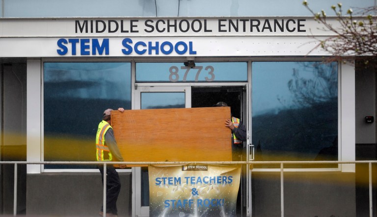 Yellow caution tape blows in the wind as workers carry a sheet of plywood into the STEM Highlands Ranch school early Thursday, May 9, 2019, in Highlands Ranch, Colo. 