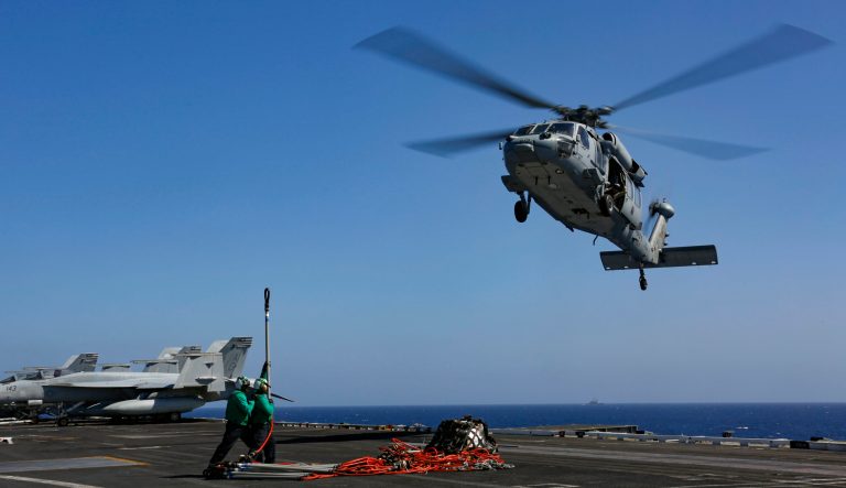 In this Friday, May 10, 2019 photo released by the U.S. Navy, logistics specialists prepare to attach cargo to an MH-60S Sea Hawk helicopter on the flight deck the Nimitz-class aircraft carrier USS Abraham Lincoln in the  Persian Gulf. The  aircraft carrier strike group is being deployed to the Persian Gulf to counter an alleged but still-unspecified threat from Iran. 