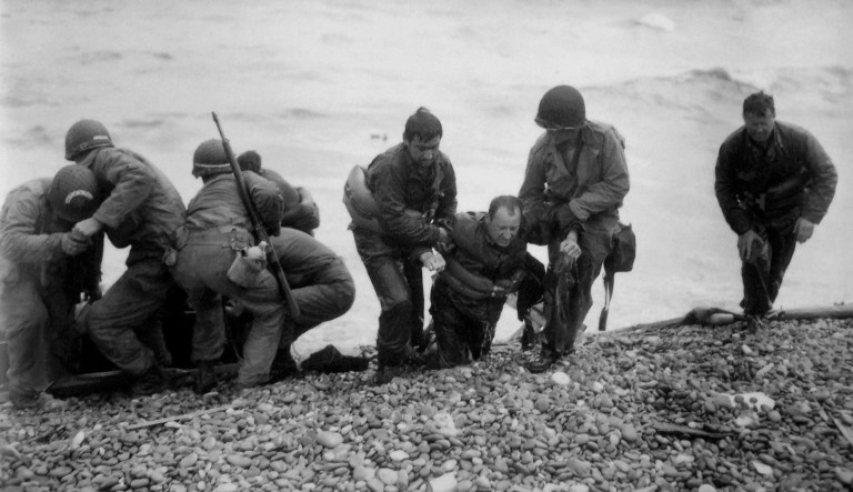In this June 6, 1944 photo, members of an American landing unit help their comrades ashore during the Normandy invasion.