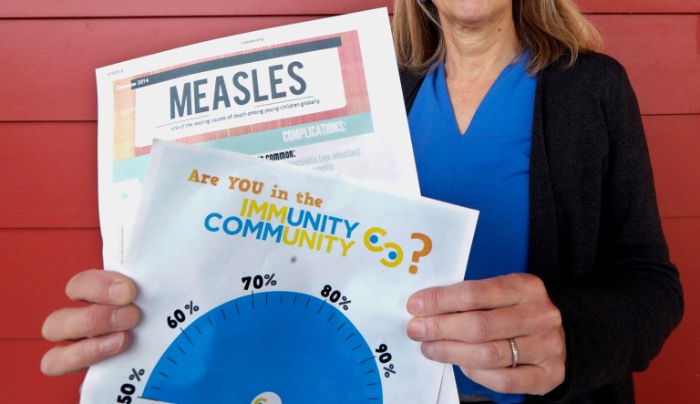 Vashon Island High School nurse Sarah Day holds information about measles vaccinations as she poses for a photo in Vashon Island, Wash.