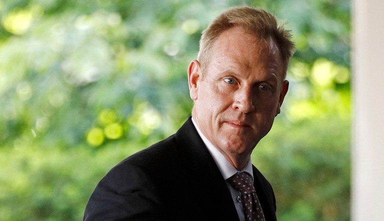 Acting Defense Secretary Patrick Shanahan walks to a door.