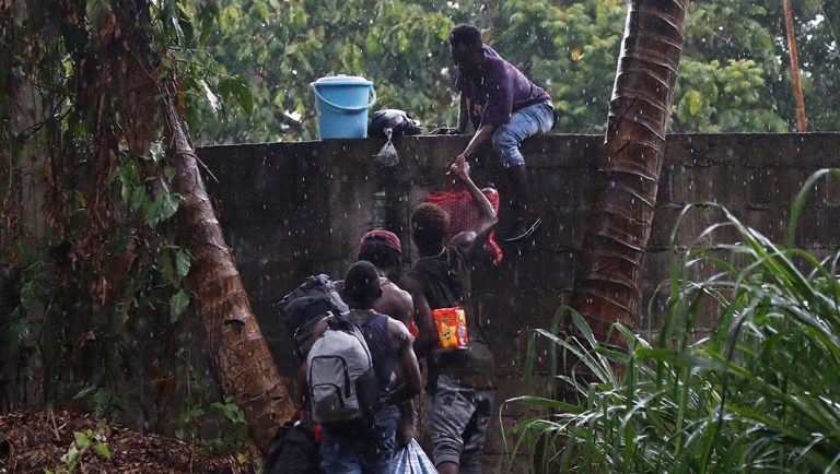 Haitian migrants jump the wall of the Mesoamericana fairgrounds to look for food, in Tapachula, Chiapas state, Mexico.