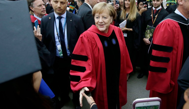 German Chancellor Angela Merkel greets graduating Harvard students as she walks in a procession though Harvard Yard at the start of Harvard University commencement exercises, Thursday, May 30, 2019, in Cambridge, Mass.