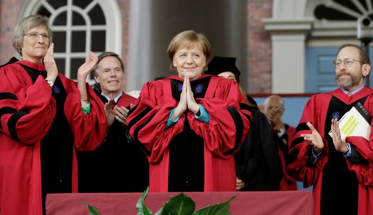 German Chancellor Angela Merkel, center, places her hands together as she receives applause while being presented with an honorary Doctor of Laws degree as former Harvard President Drew Faust, left, and Harvard Provost Alan Garber, right, look on during Harvard University commencement exercises, Thursday, May 30, 2019, on the schools campus, in Cambridge, Mass. 