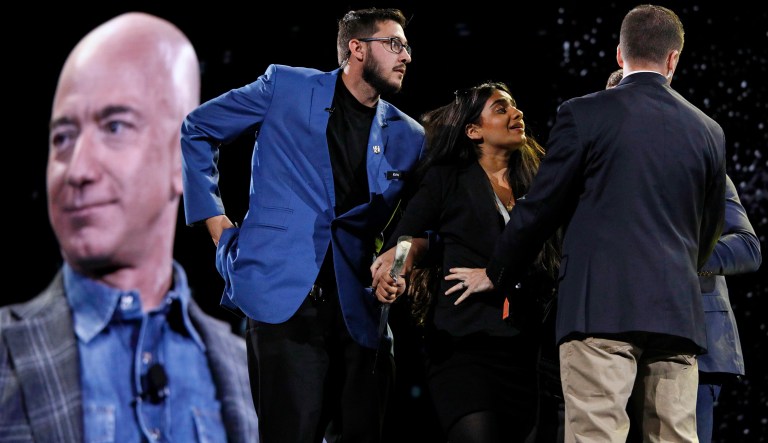 Security removes a protestor, second from left, from the stage as Amazon CEO Jeff Bezos speaks at the the Amazon re:MARS convention, Thursday, June 6, 2019, in Las Vegas.