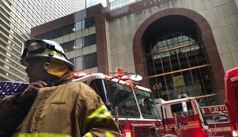 A New York City firefighter responds to the scene where a helicopter crash-landed on the roof of a midtown Manhattan skyscraper in New York.
