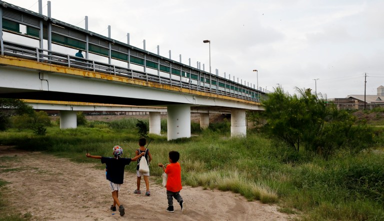 Migrant children walk with their families along the Rio Grande, as pedestrian commuters use the Puerta Mexico bridge to enter Brownsville, Texas, seen from Matamoros, Tamaulipas state, Mexico.