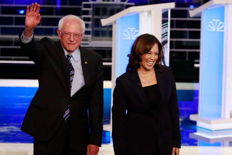 Democratic presidential candidates Sen. Bernie Sanders, I-Vt., and Sen. Kamala Harris, D-Calif. stand on the stage before the start of a Democratic primary debate hosted by NBC News at the Adrienne Arsht Center for the Performing Arts in Miami.