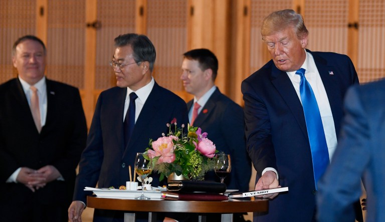 President Trump, right, sets down his copy of the band Exo's album Love Shot during a visit with South Korean President Moon Jae-in, second from left, at the tea house on the grounds of the Blue House in Seoul, South Korea.