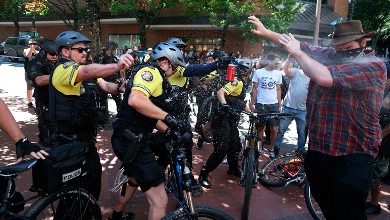 After a confrontation between authorities and protestors, police use pepper spray as multiple groups, including Rose City Antifa, the Proud Boys and others protest in downtown Portland, Ore., on Saturday, June 29, 2019. In separate social media posts later in the day, police declared the situation to be a civil disturbance and warned participants faced arrest. (Dave Killen/The Oregonian via AP)