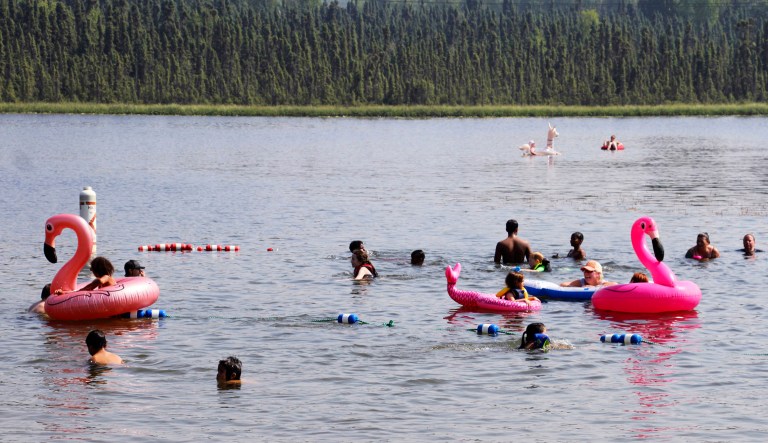 Children play with inflatable flamingos and other creatures at Goose Lake Friday in Anchorage, Alaska.