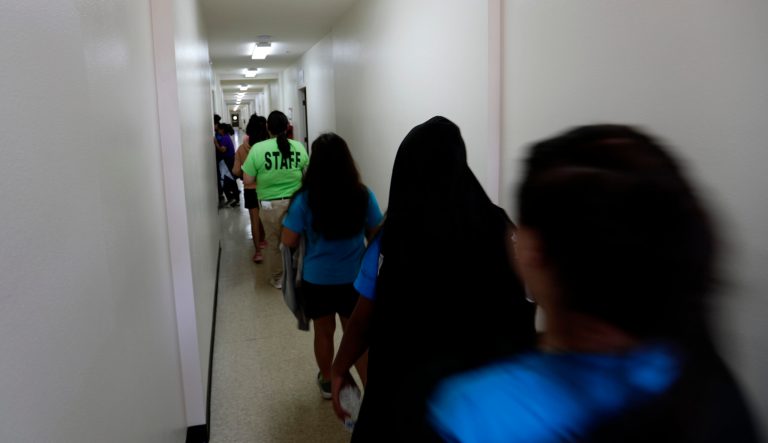 Immigrants walk down the hall of a dormitory at the U.S. government's newest holding center for migrant children in Carrizo Springs, Texas, Tuesday, July 9, 2019.  