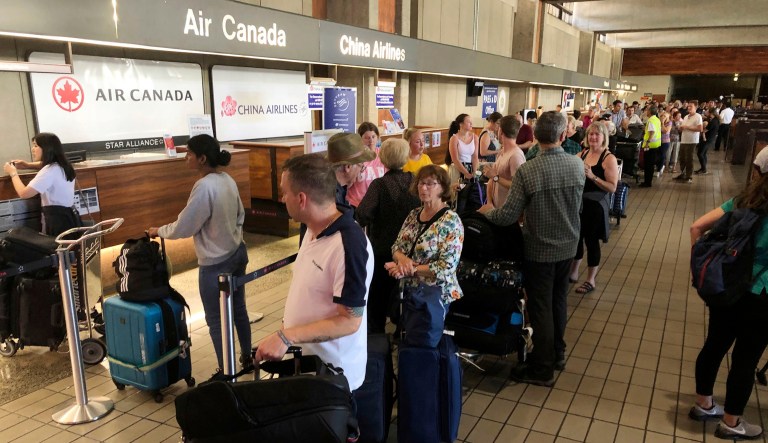 Passengers from an Australia-bound Air Canada flight diverted to Honolulu Thursday, July 11, 2019, after about 35 people were injured during turbulence, stand in line at the Air Canada counter at Daniel K. Inouye International Airport to rebook flights.