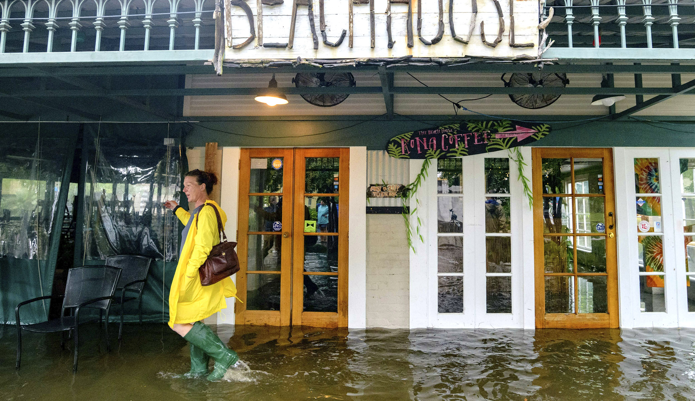 Aimee Cutter, the owner of Beach House restaurant, walks through water surge from Lake Pontchartrain on Lakeshore Drive in Mandeville, Louisiana.