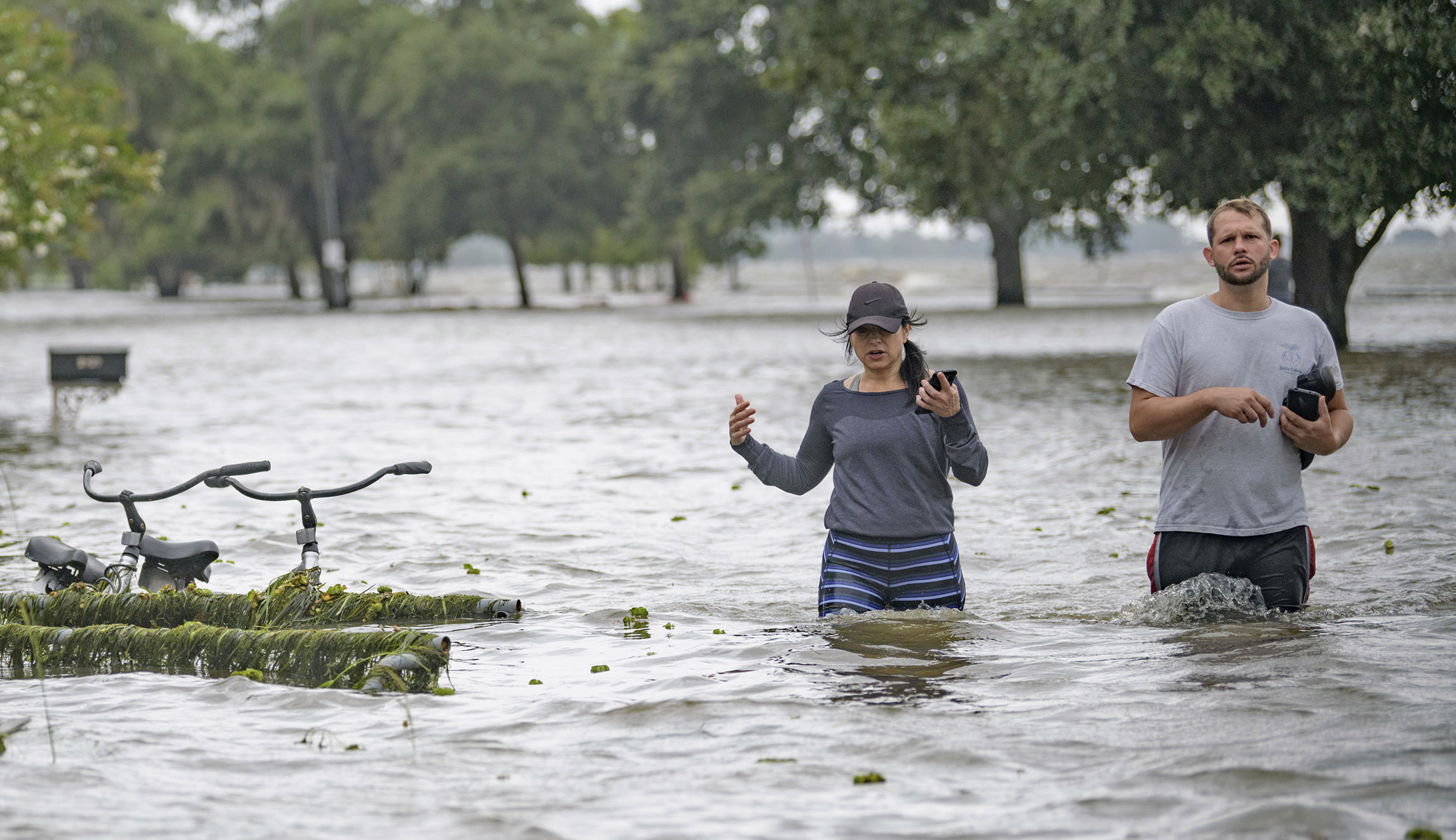 Collen Schiller and Wesley Vinson wade through storm surge from Lake Pontchartrain on Lakeshore Drive in Mandeville, La., Saturday. The waves are caused by the wind and storm surge from Barry in the Gulf of Mexico. Mandeville is on the north shore of the lake, while New Orleans is on the south shore. 