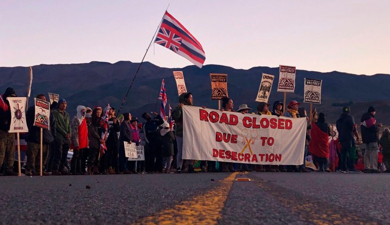 Demonstrators are gather to block a road at the base of Hawaii's tallest mountain, Monday, July 15, 2019, in Mauna Kea, Hawaii, to protest the construction of a giant telescope on land that some Native Hawaiians consider sacred. 