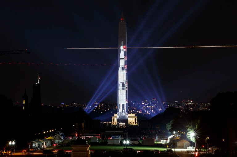 A 363-foot Saturn V rocket is projected on the east face of the Washington Monument.