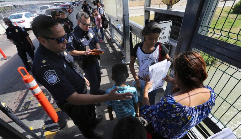 A United States Customs and Border Protection Officer checks the documents of migrants before being taken to apply for asylum in the United States on the International Bridge 1 in Nuevo Laredo, Mexico.