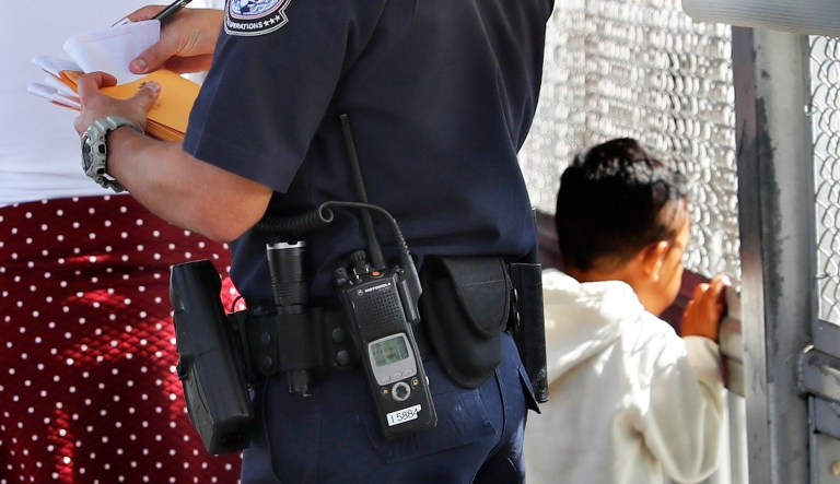 A United States Customs and Border Protection Officer checks the documents of migrants, before being taken to apply for asylum in the United States, on the International Bridge 1 in Nuevo Laredo, Mexico.