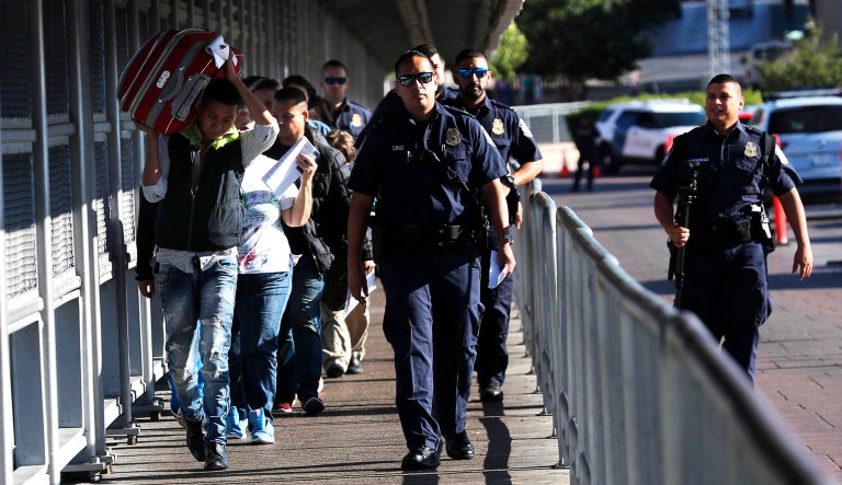 U.S. Customs and Border Protection agents escort Central American migrants across International Bridge 1 Las Americas from Laredo, Texas, to Nuevo Laredo, Mexico.