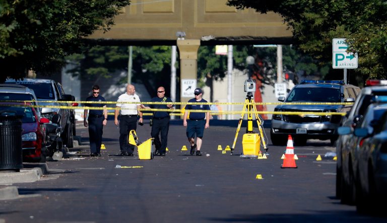 Authorities walk among evidence markers at the scene of a mass shooting, Sunday, Aug. 4, 2019, in Dayton, Ohio.