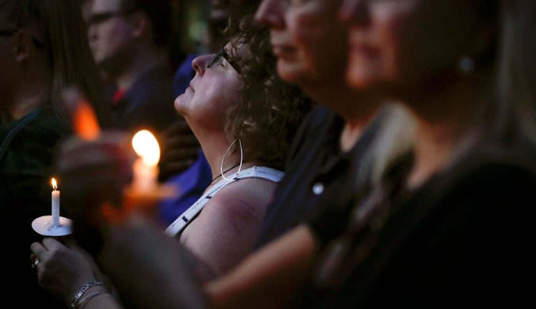 Mourners pause for a prayer as they gather for a vigil at the scene of a mass shooting, Sunday, Aug. 4, 2019, in Dayton, Ohio. 