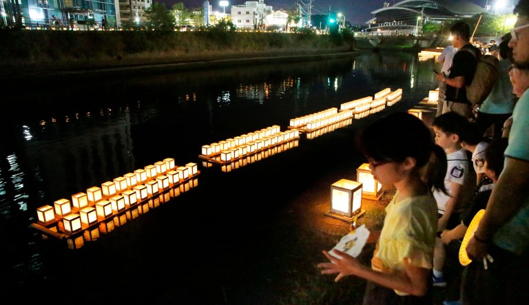 Children look at "Light of Peace" lanterns float on the Uragami River in Nagasaki, Japan, on Friday. Nagasaki marked the 74th anniversary of the atomic bombing on Friday.